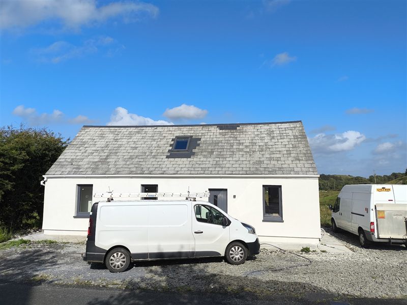 Renovated single-storey cottage with crisp white render, grey windows and a slate roof with a rooflight