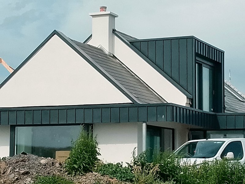 Dormer and single-storey extension finished in dark standing-seam zinc cladding on a white rendered house